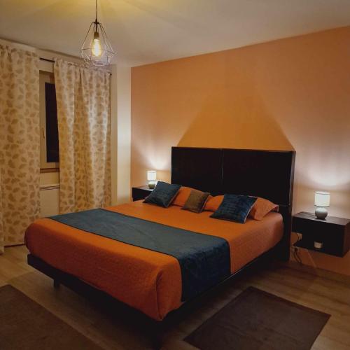 um quarto com uma cama grande e um cobertor laranja em les chambres de Sandra em Volognat