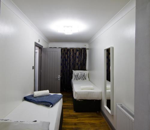 Hatch EndにあるSleek 3Bed/3Bathroom Flat@Harrowの小さな部屋で、ベッド2台、鏡が備わります。