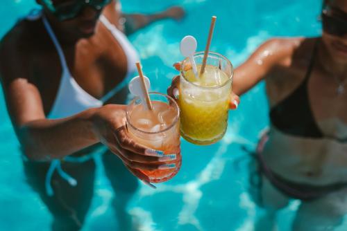 two people holding a drink in a swimming pool at Hotel LLITERAS in Cala Ratjada