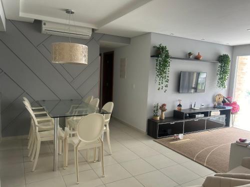 a dining room with a glass table and white chairs at Apartamento na Riviera de Sao Lourenco in Riviera de São Lourenço