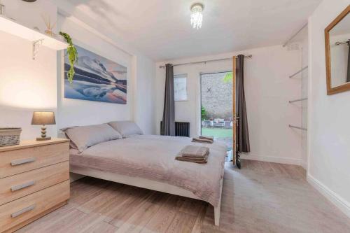 a bedroom with a bed and a dresser and a window at Spacious and modern London duplex apartment with garden in London