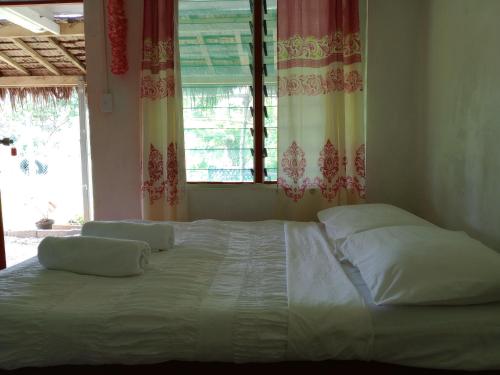 um quarto com uma cama grande com almofadas e uma janela em Kathy B Guesthouse em Luganville