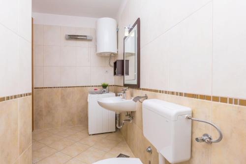 een badkamer met een wastafel, een toilet en een spiegel bij Apartment Galeria in Omiš