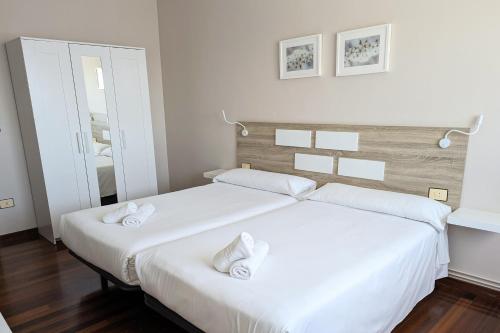2 camas blancas en una habitación con espejo en Apartamentos Turísticos Guillermo en Palas de Rei 