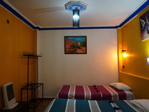 a room with two beds and a tv in it at La Kasbah Elkhorbat Muxu Berbere in Asrir