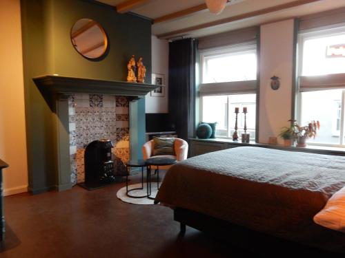a bedroom with a fireplace and a bed and a chair at Gasthuis In de Heilige Stede in Hasselt