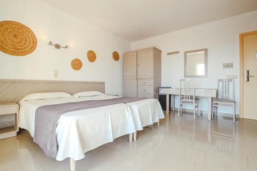ein weißes Schlafzimmer mit einem Bett und einem Schreibtisch in der Unterkunft Hotel LLITERAS in Cala Ratjada