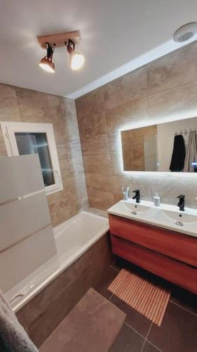 une salle de bain avec une baignoire blanche, un lavabo et un miroir dans l'établissement Maison neuve proche station de ski, 10 couchages, tout confort, à Granieu