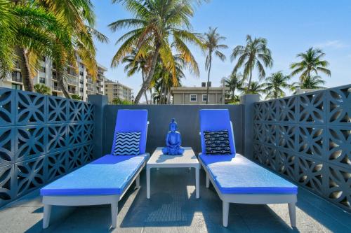 two blue chairs and a table on a patio with palm trees at Sunshine shores boutique apartments in Palm Beach Shores
