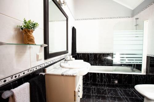 y baño en blanco y negro con lavabo y bañera. en Villa Margarida, en Ponta do Sol