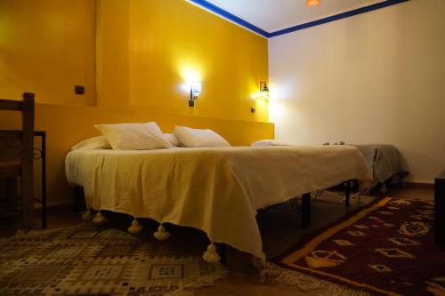 a bedroom with a bed with a yellow wall at La Kasbah Elkhorbat Muxu Berbere in Asrir