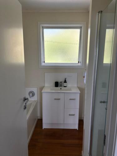 baño con lavabo blanco y ventana en Rotorua Lakes House en Rotorua