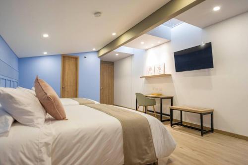 a bedroom with a bed and a table and a television at Siete Balcones Hotel Coworking in Pasto