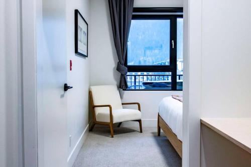 a bedroom with a bed and a chair and a window at Tumbledown Condo by Revelstoke Vacations in Revelstoke