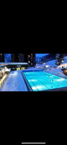 - une vue sur une grande piscine la nuit dans l'établissement Studio tout confort pied des pistes avec balcon et wifi, à Villarembert