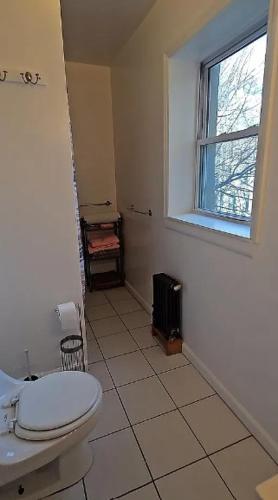 a bathroom with a toilet and a window at Sylish 1 Bedroom Apartment in NYC! in New York