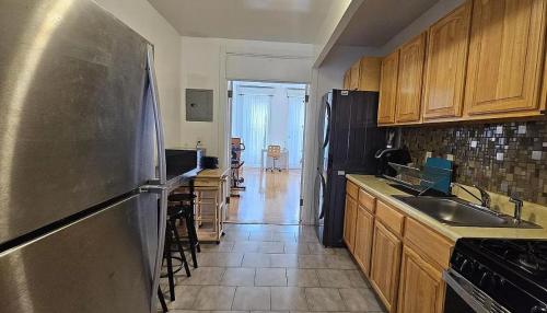 una cocina con nevera de acero inoxidable y armarios de madera en Sylish 1 Bedroom Apartment in NYC!, en Nueva York