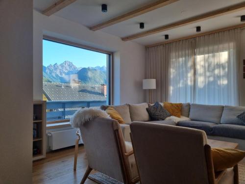a living room with a couch and a large window at Comfy mountain nest in Mojstrana