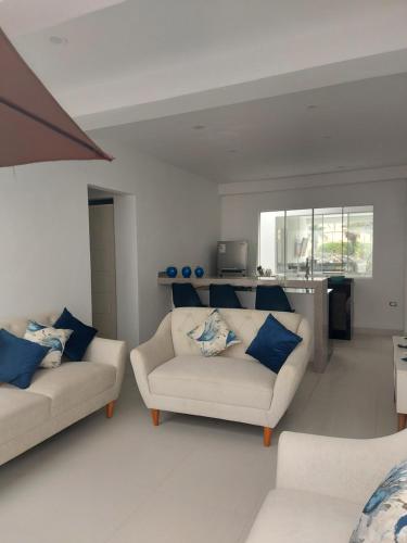 a living room with two white couches and blue pillows at Departamento de playa amoblado in Cerro Azul