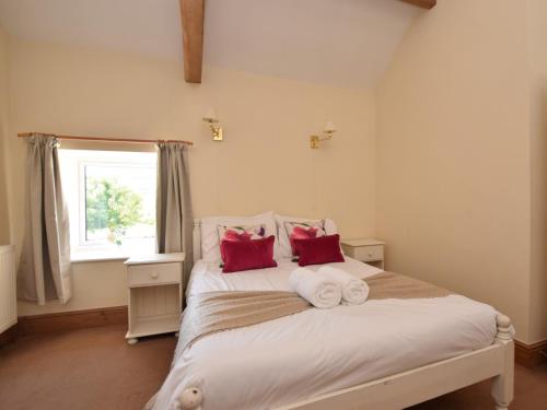 a bedroom with a white bed with red pillows at 3 Bed in Ashford in the Water PK501 in Great Longstone