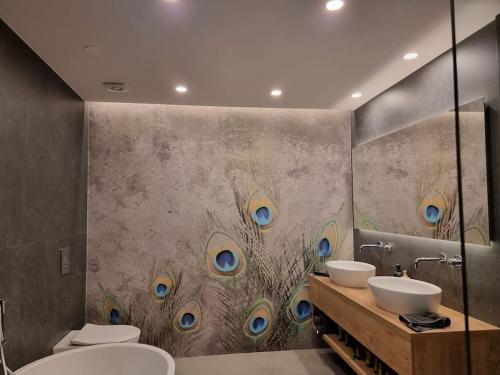 uma casa de banho com dois lavatórios e penas de pavão na parede em Comfy mountain nest em Mojstrana