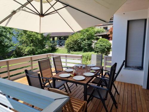 a wooden table with chairs and an umbrella on a deck at Comfy mountain nest in Mojstrana