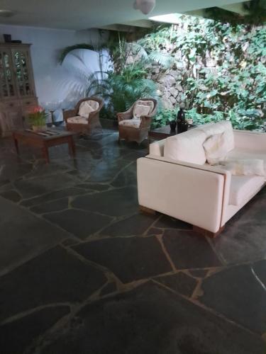 a living room with a white couch and chairs at Mansão Mar casado in Guarujá