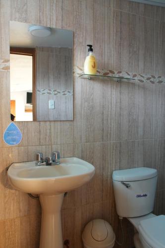 W łazience znajduje się umywalka, toaleta i lustro. w obiekcie MATARA GREENS HOTEL w Cuzco