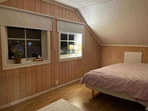 a bedroom with a bed and two windows at 54:an - flott rekkehus med gangavstand til sentrum in Røros