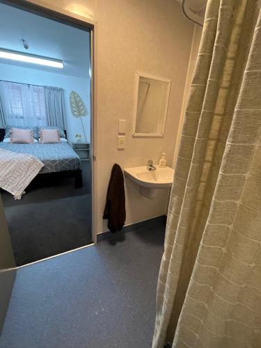 a bathroom with a bed and a sink and a mirror at Kaikoura Seaside lodge in Kaikoura