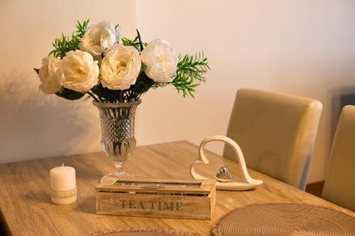 a vase of white roses sitting on a table at Apartmany u tri jehnatek in Karlovy Vary
