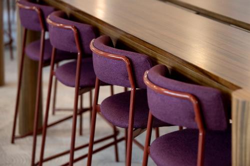 a row of purple chairs sitting next to a counter at Mercure Sydney Blacktown in Blacktown