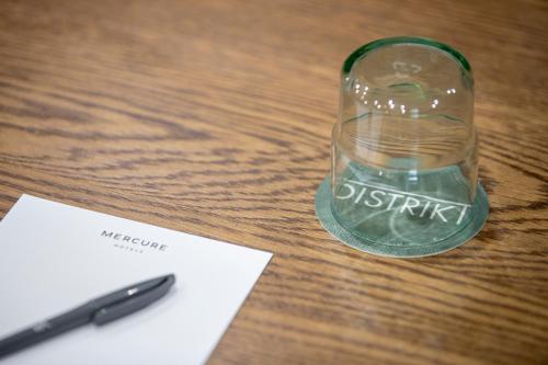 a glass bottle sitting on a table next to a pen at Mercure Sydney Blacktown in Blacktown