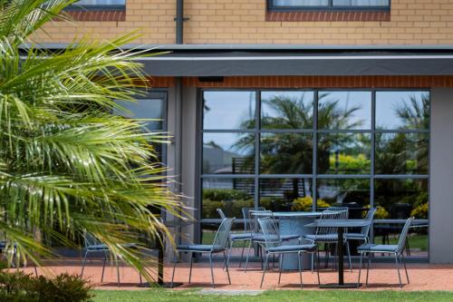 a group of chairs and tables in front of a building at Mercure Sydney Blacktown in Blacktown