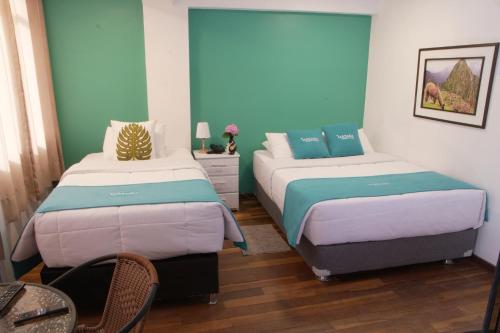 MATARA GREENS HOTEL في كوسكو: سريرين في غرفة باللون الأزرق والأبيض