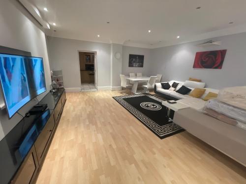 ein Wohnzimmer mit einem Sofa und einem Flachbild-TV in der Unterkunft Deluxe Room En-suite Free Parking in Seven Kings
