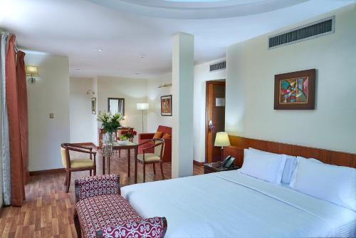 Habitación de hotel con cama, mesa y sillas en Hotel Cityzen Guayaquil, en Guayaquil