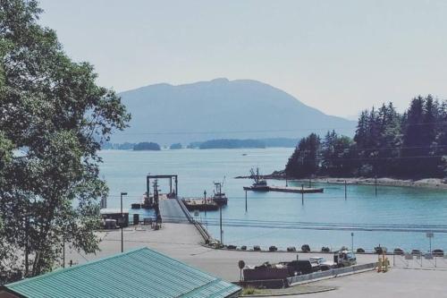 un quai avec des bateaux dans un lac avec une montagne dans l'établissement Auk Nu, Cove View Alaskan Home, à Mendenhaven