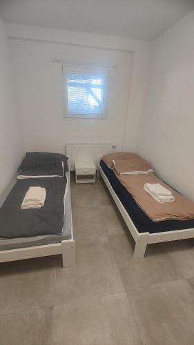 2 łóżka pojedyncze w pokoju z oknem w obiekcie Vu's Home w Pradze