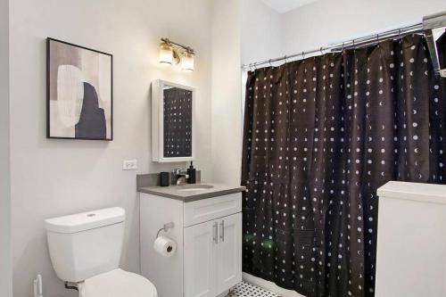 a bathroom with a toilet and a black shower curtain at Roomy & Inviting 3BR Chicago Apartment - 53rd St 2E in Chicago