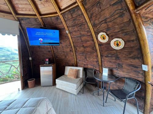 a room with a tv in a wooden wall at Eco glamping Santillana in Charalá
