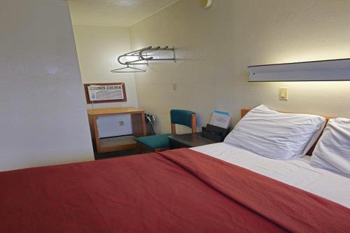 a bedroom with a bed with a red blanket and a desk at Home Motel Abbotsford in Abbotsford