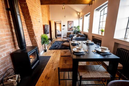 ein Wohnzimmer mit einem Tisch und einem Holzofen in der Unterkunft VIP 3BR Grade2 Luxurious Industrial House with WOOD FIRE, Electric blinds and big Cast iron Windows in the heart of the JQ in Birmingham