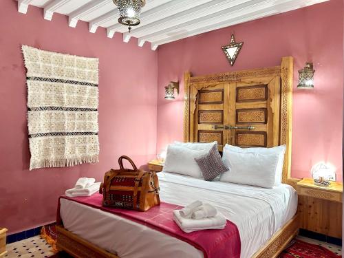 um quarto com paredes cor-de-rosa e uma cama com um saco. em Riad Noor Medina em Fez