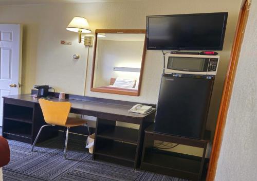 a room with a desk with a television and a mirror at Home Motel Abbotsford in Abbotsford