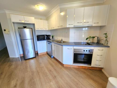 a kitchen with white cabinets and a stainless steel refrigerator at Fairways Golf & Beach Retreat Bribie Island in Woorim