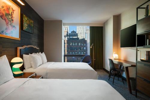 a hotel room with two beds and a desk at Renaissance New York Chelsea Hotel in New York