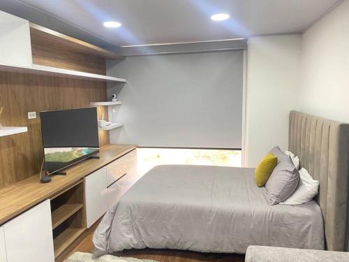 a bedroom with a bed and a flat screen tv at Hermoso Loft en North Point in Bogotá