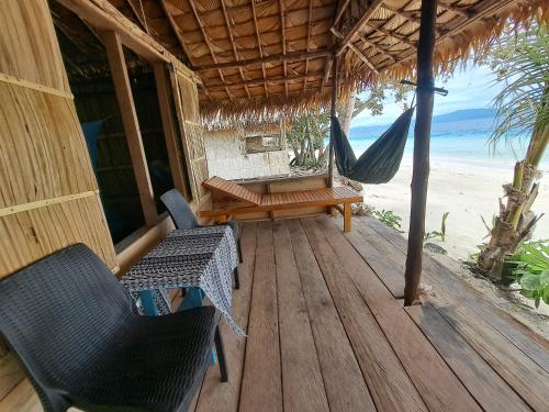 a porch with a hammock and a table and chairs at Raja Ampat Jousuba Homestay in Minyaifuin