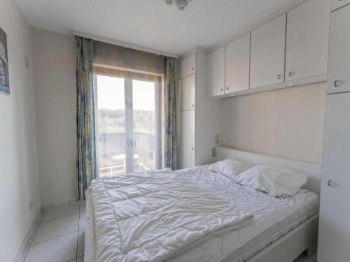 Un dormitorio blanco con una cama grande y una ventana en Plaza E2413 with beautiful sea views, en Oostduinkerke